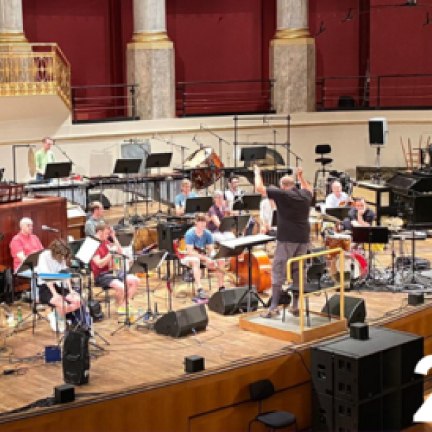 Ein Orchester probt auf einer Bühne in einem Konzertsaal.