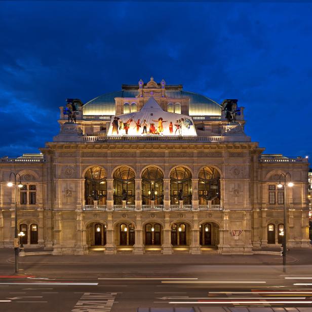 Die Wiener Staatsoper erstrahlt im Abendlicht unter einem tiefblauen Himmel.