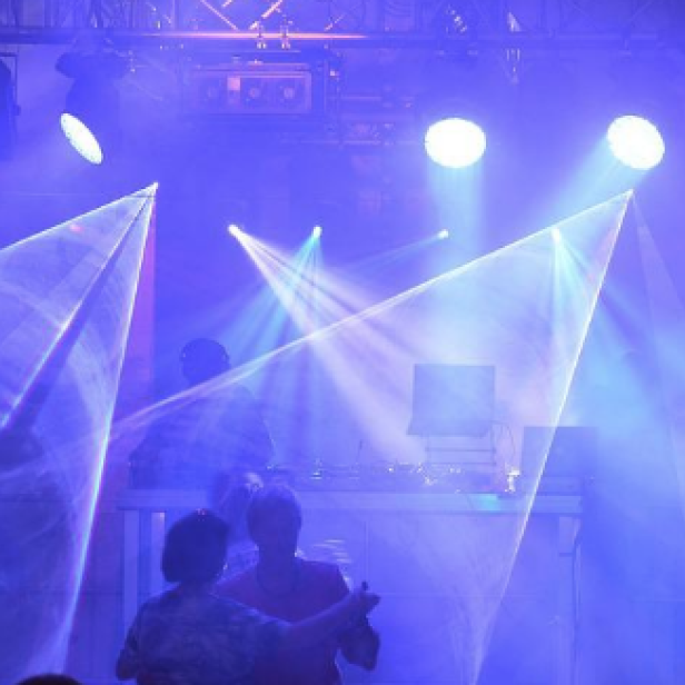 Tanzende Menschenmenge unter blauem Laserlicht in einem Club.