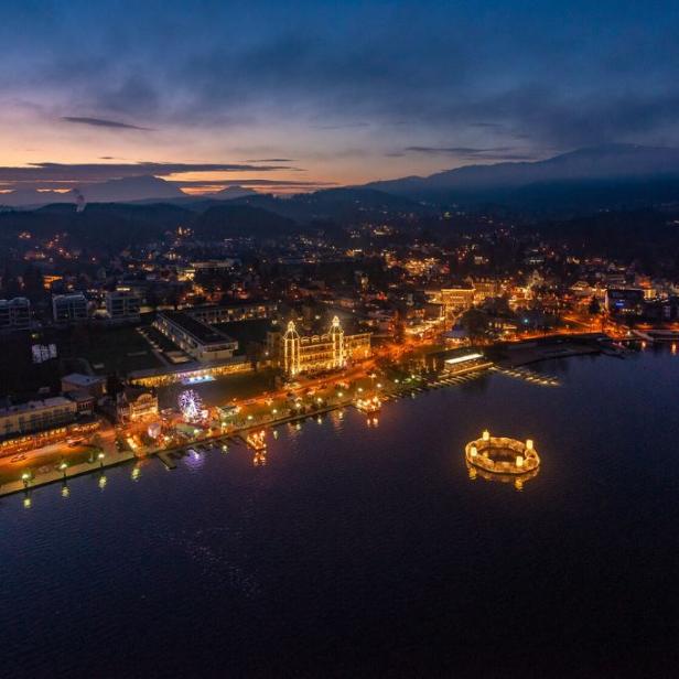 Ein nächtlicher Blick auf eine Stadt am See, beleuchtet mit Lichtern bei Dämmerung.