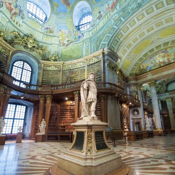 Die Österreichische Nationalbibliothek in Wien mit einer Statue im Vordergrund.
