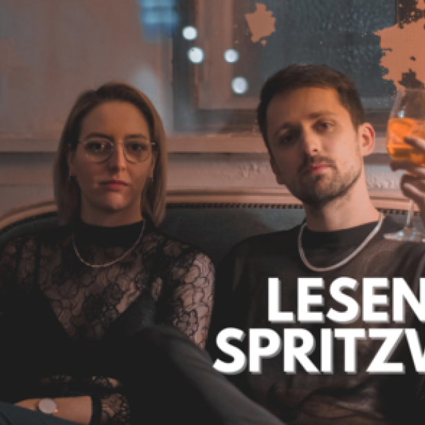 Eine Frau und ein Mann sitzen mit je einem Glas Spritzwein in einem Raum.