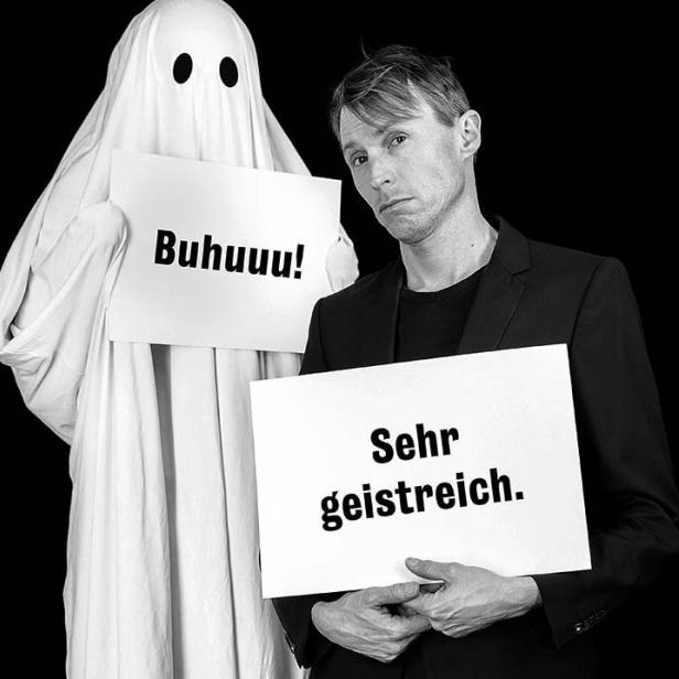 Ein Mann im Anzug posiert mit einem Geist, beide halten Schilder hoch.
