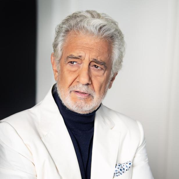 Plácido Domingo mit verschränkten Armen in einem weißen Anzug.