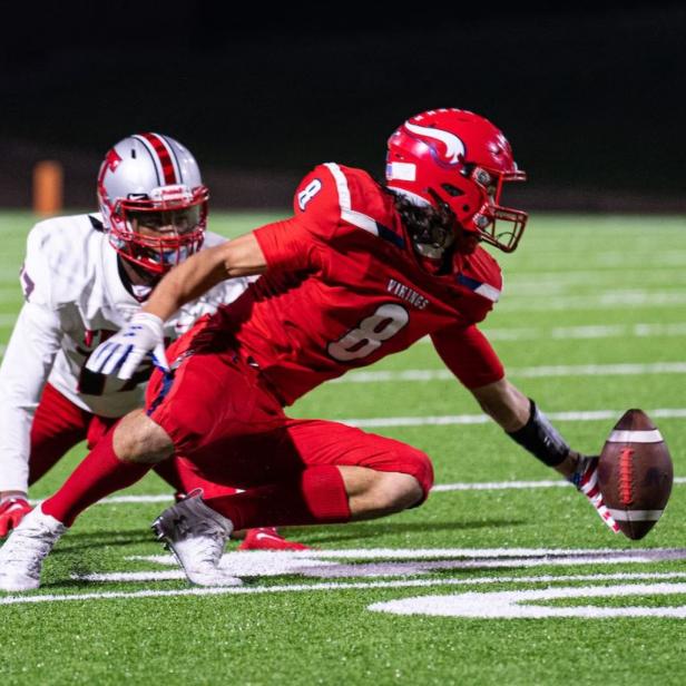 Ein Footballspieler in roter Uniform versucht, den Ball zu fangen.