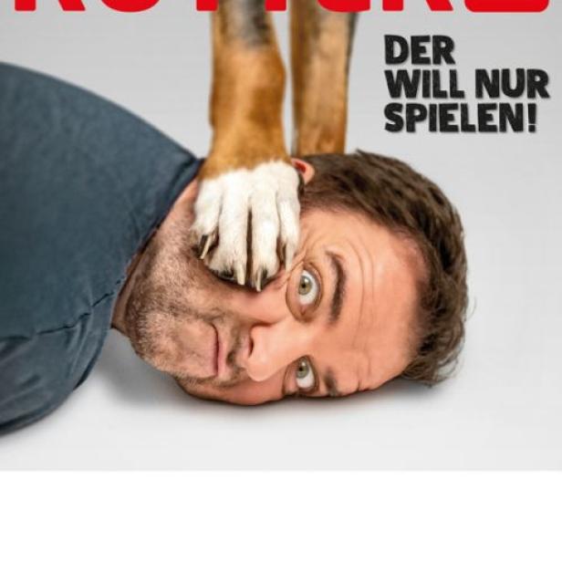 Martin Rütter liegt am Boden, während ein Hund seine Pfote auf sein Gesicht legt.
