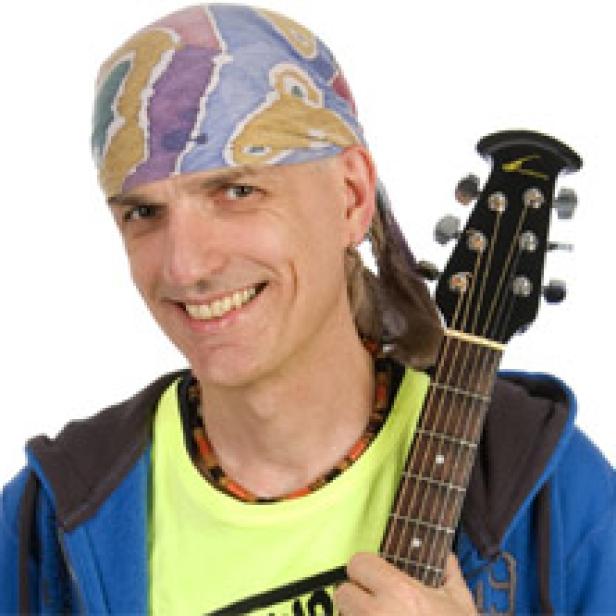Ein lächelnder Mann mit einem bunten Kopftuch hält eine Gitarre.