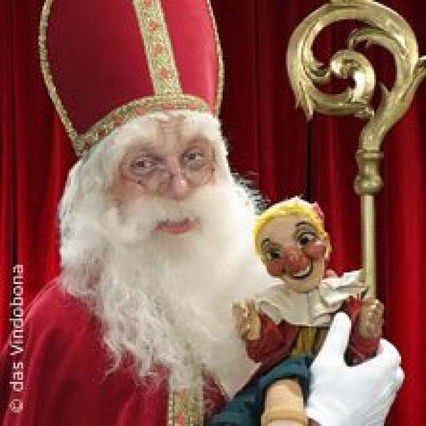 Ein als Nikolaus verkleideter Mann hält eine Pinocchio-Puppe in der Hand.