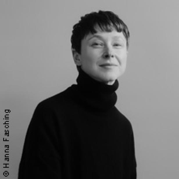 Schwarz-Weiß-Porträt einer Frau mit kurzem, dunklem Haar und einem schwarzen Rollkragenpullover.