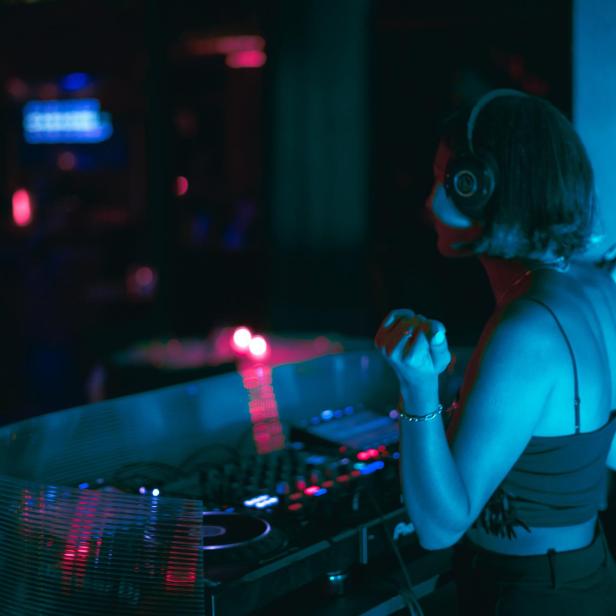 Eine DJane mit Kopfhörern legt in einem Club auf.