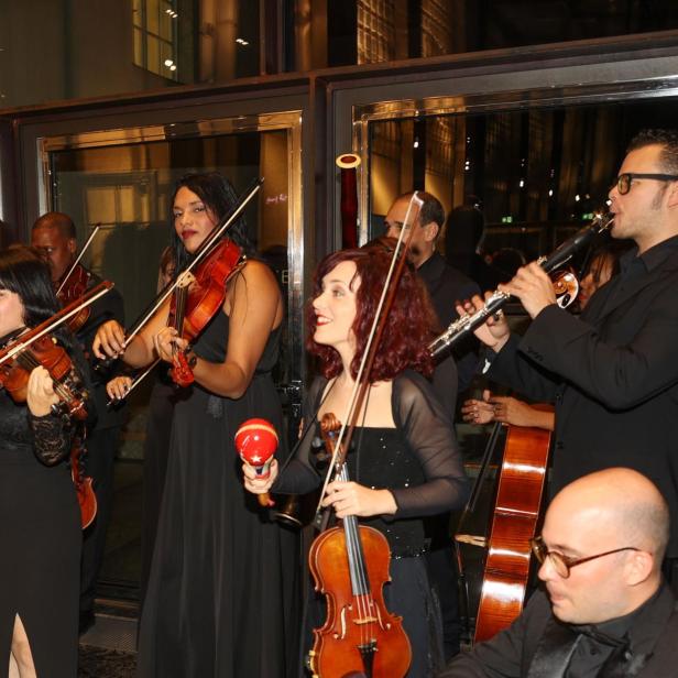 Ein Ensemble spielt auf Geigen, Klarinette und anderen Instrumenten bei einer Veranstaltung.