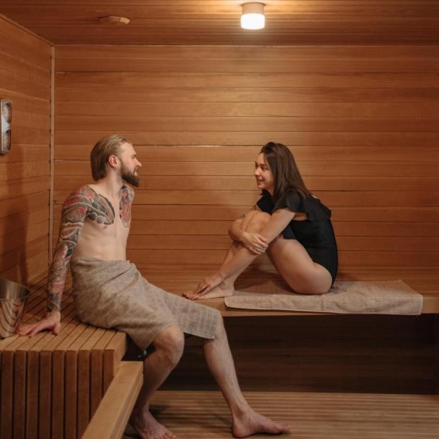 Ein Mann und eine Frau sitzen in einer Sauna.