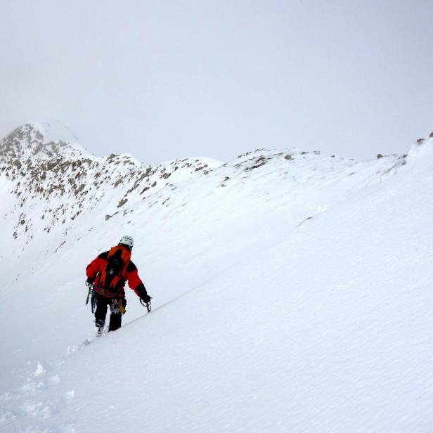 Ein Bergsteiger erklimmt einen schneebedeckten Berg.