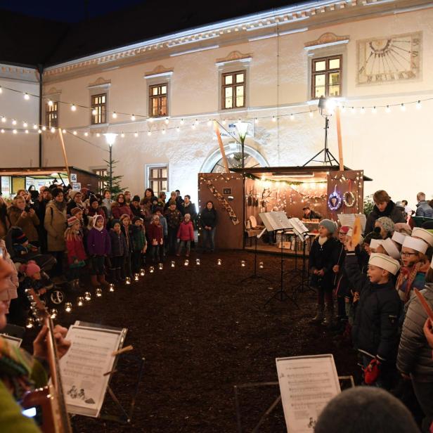 Ein Kinderchor tritt auf einem Platz mit Lichtern und Publikum auf.