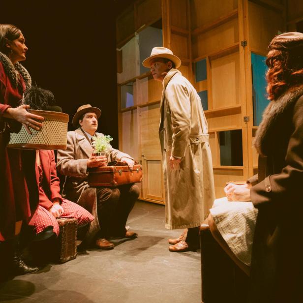 Eine Theaterszene mit mehreren Personen in Kostümen auf einer Bühne.