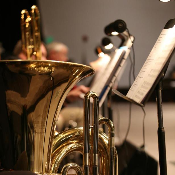 Eine goldene Tuba steht auf einer Bühne vor Notenständern.