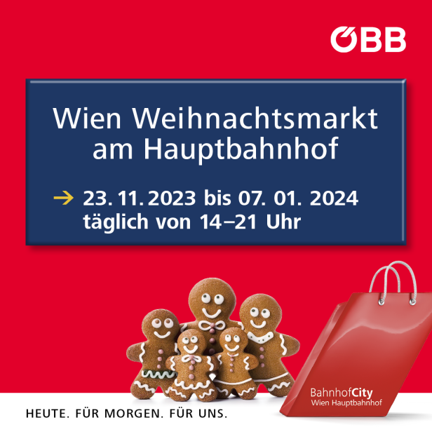 Eine Gruppe Lebkuchenfiguren vor einem Plakat für den Wiener Weihnachtsmarkt am Hauptbahnhof.