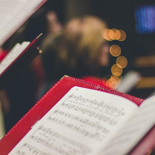 Ein Chor singt aus roten Notenbüchern.