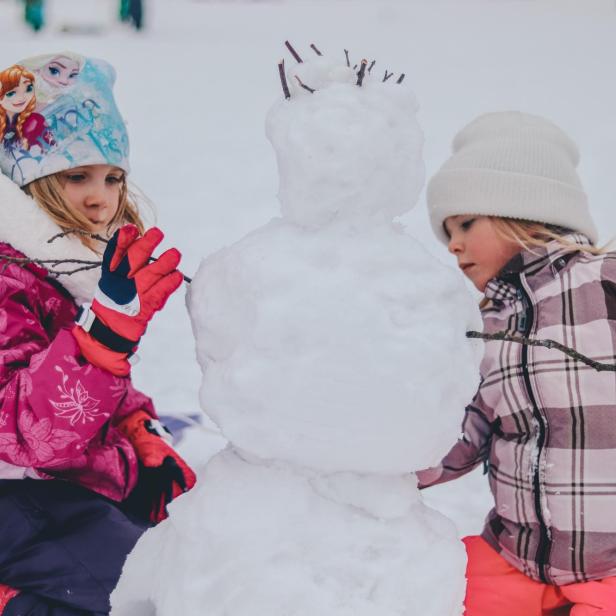 Zwei Kinder bauen einen Schneemann.