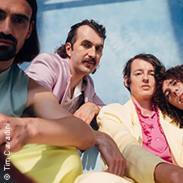 Die vier Bandmitglieder von Parcels posieren vor einem hellblauen Hintergrund.
