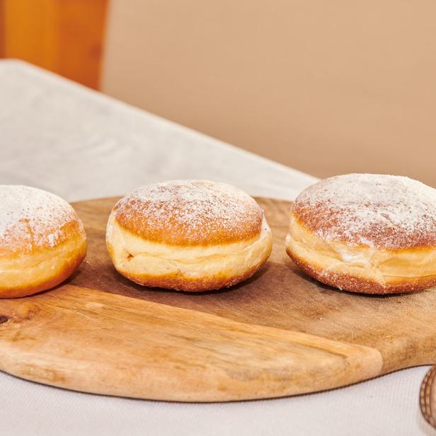 Drei Krapfen einer Reihe auf einer Holzplatte