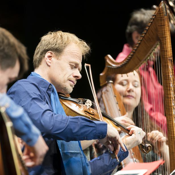 Ein Ensemble spielt auf der Bühne Violine, Harfe, Gitarre und Kontrabass.