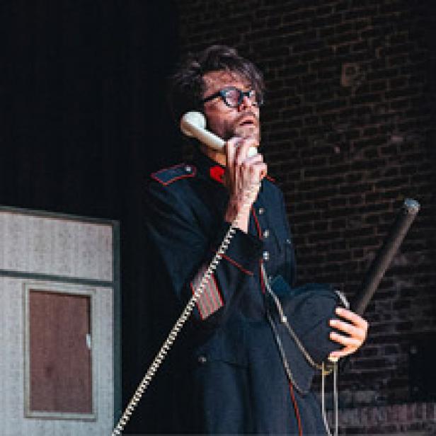 Ein Mann in Uniform telefoniert mit einem alten Telefonhörer.