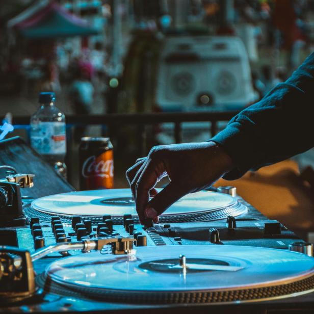 Ein DJ bedient ein Mischpult mit zwei Plattenspielern.