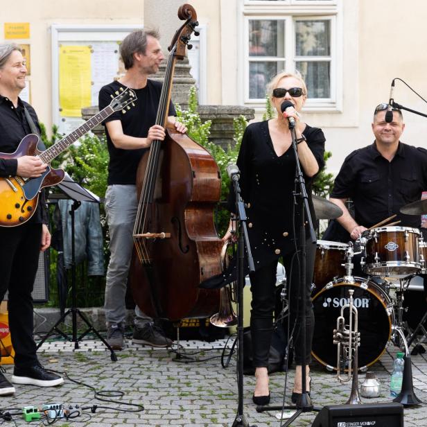 Eine Jazzband spielt im Freien mit Sängerin, Gitarrist, Bassist und Schlagzeuger.