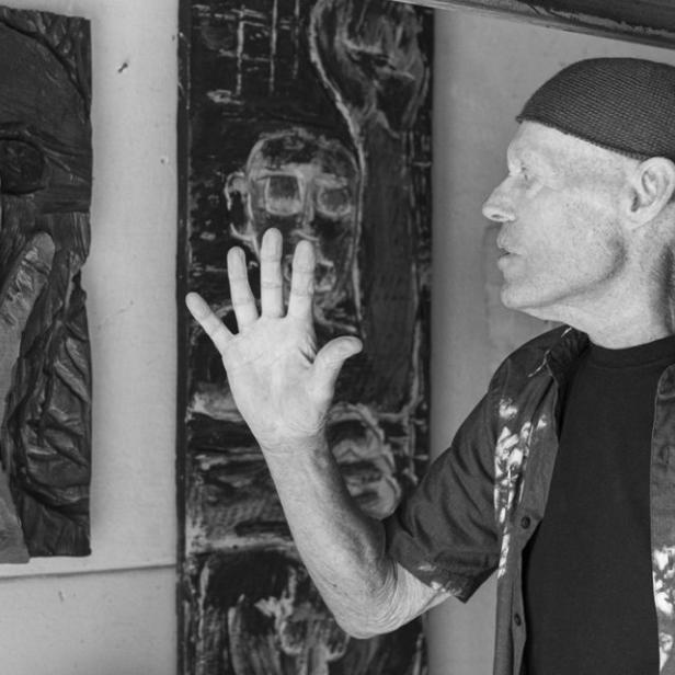 Ein Mann betrachtet Holzschnitzereien in einem Atelier.
