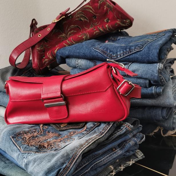 Ein Stapel Jeans mit zwei roten Handtaschen darauf.