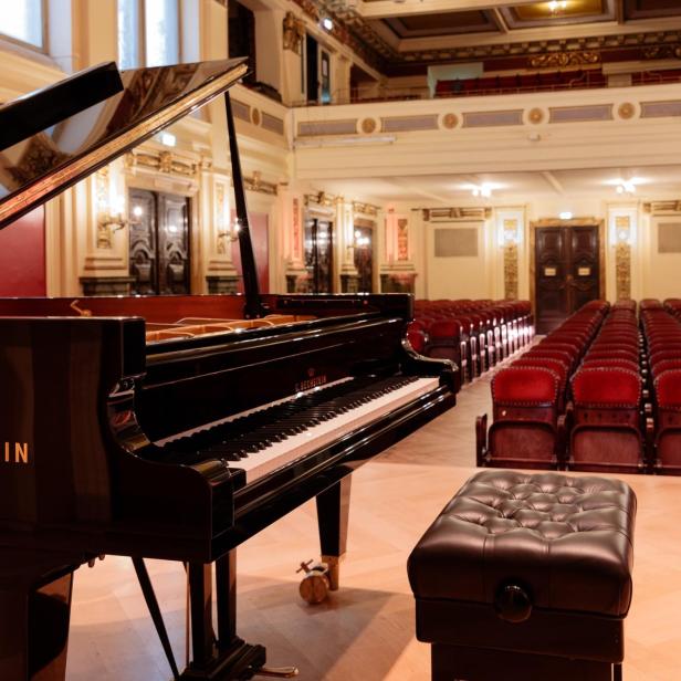 Ein C. Bechstein Flügel steht in einem leeren Konzertsaal mit roten Sitzen.