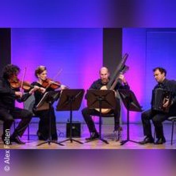 Ein Streichquartett spielt auf einer Bühne vor einem violetten Hintergrund.