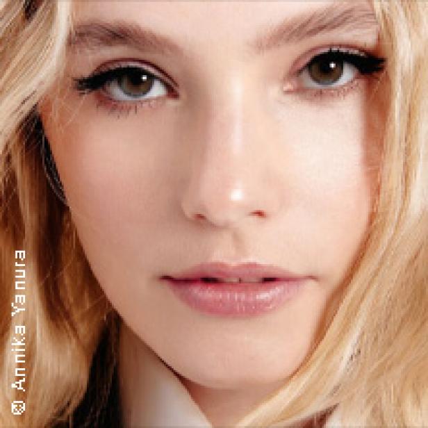 Nahaufnahme des Gesichts einer jungen Frau mit blonden Haaren und hellen Augen.