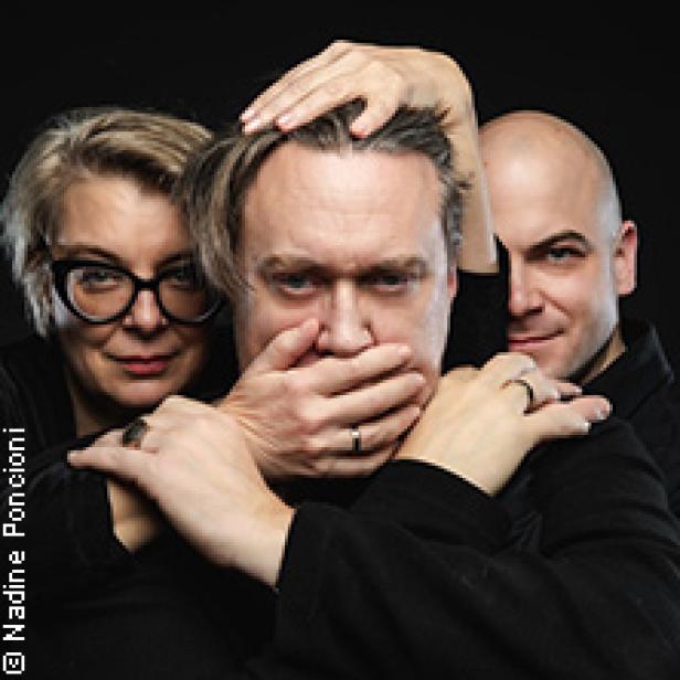 Eine Frau und ein Mann halten einem anderen Mann Mund und Augen zu.