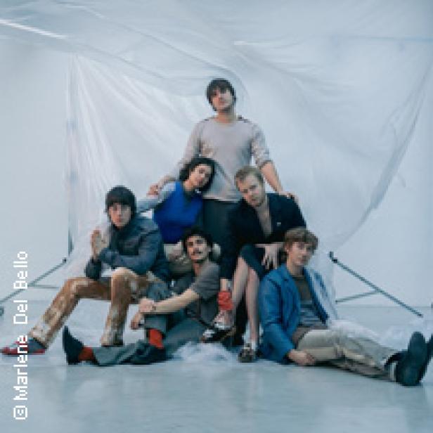 Eine Gruppe von sechs Personen posiert vor einem weißen, transparenten Hintergrund.