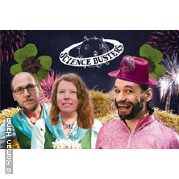 Die Science Busters präsentieren sich vor einem festlichen Hintergrund mit Feuerwerk und Glücksklee.