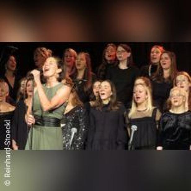 Ein Chor singt auf einer Bühne in Mikrofone.