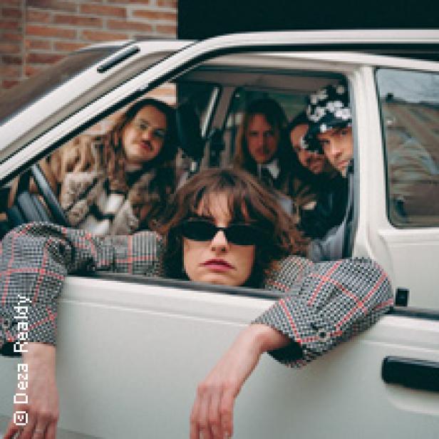 Eine Gruppe von Personen sitzt in einem weißen Auto und posiert für ein Foto.