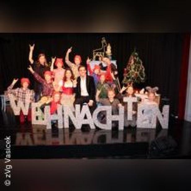 Eine Gruppe von Menschen posiert mit dem Wort „Weihnachten“ auf einer Bühne.