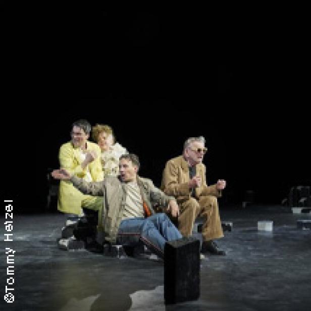 Fünf Schauspieler sitzen oder stehen auf einer Bühne vor einem schwarzen Hintergrund.