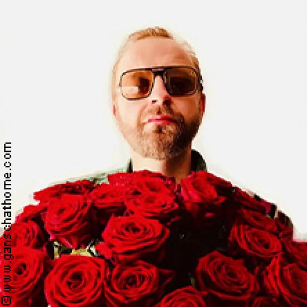 Ein Mann mit Sonnenbrille hält einen großen Strauß roter Rosen.