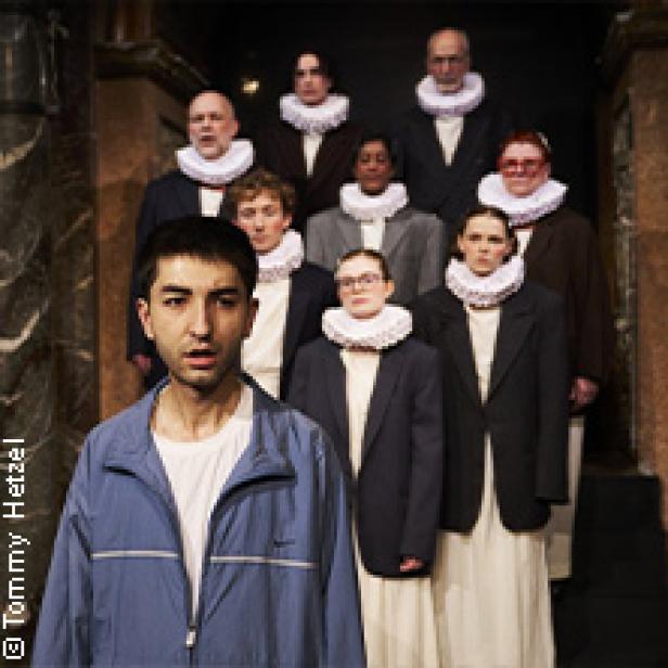 Eine Gruppe von Schauspielern in historischen Kostümen und ein Mann in Trainingsjacke stehen vor einer Treppe.