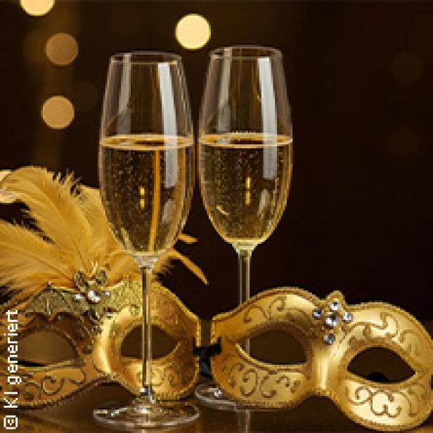 Zwei Sektgläser stehen vor goldenen Karnevalsmasken.