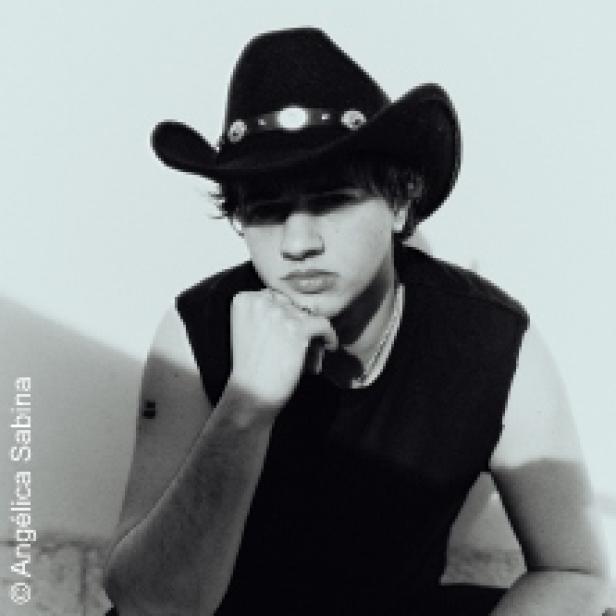 Ein junger Mann mit Cowboyhut posiert in einem schwarzen Tanktop.