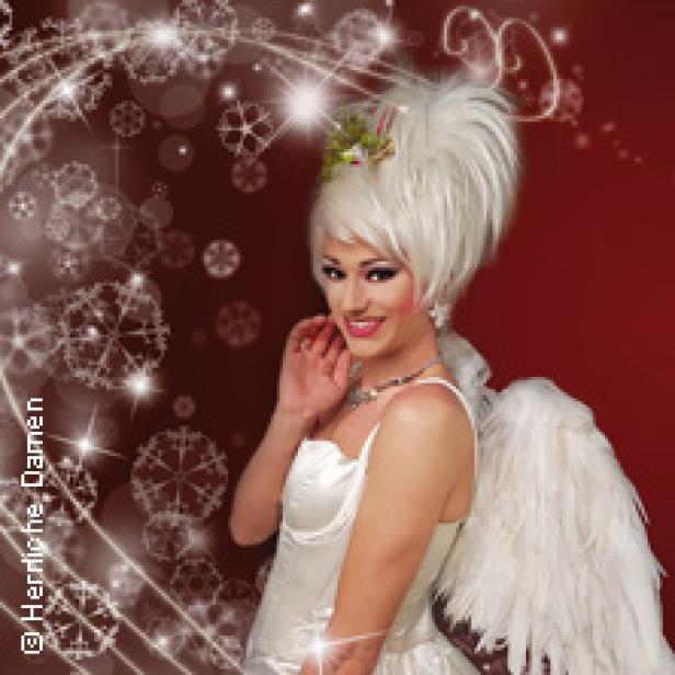 Eine Dragqueen in einem weißen Engelkostüm vor einem roten Hintergrund mit Schneeflocken.