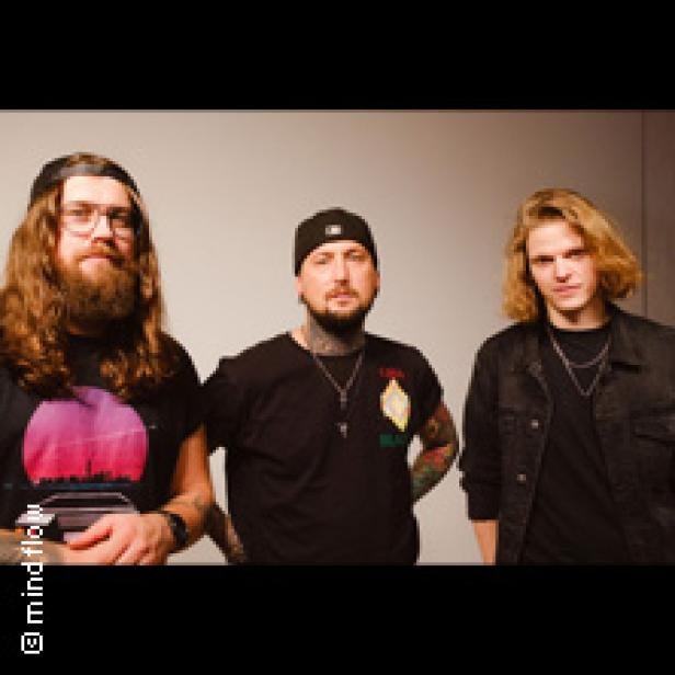 Drei Männer stehen vor einer grauen Wand.