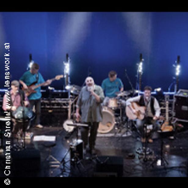 Eine Band spielt auf einer Bühne mit blauem Hintergrund.
