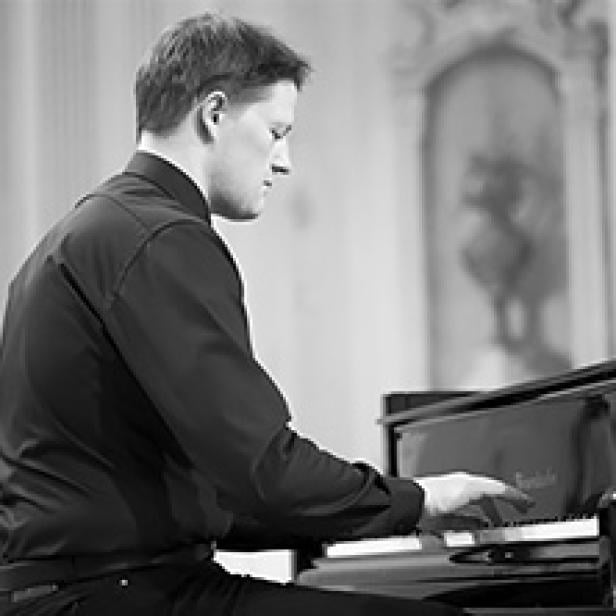 Ein Mann spielt Klavier in einem Konzertsaal.