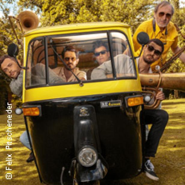 Eine Band posiert mit ihren Instrumenten vor und in einem gelben Tuk-Tuk.